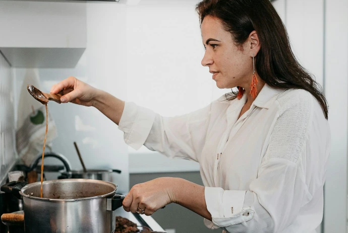 woman in white dress shirt holding stainless steel cooking pot